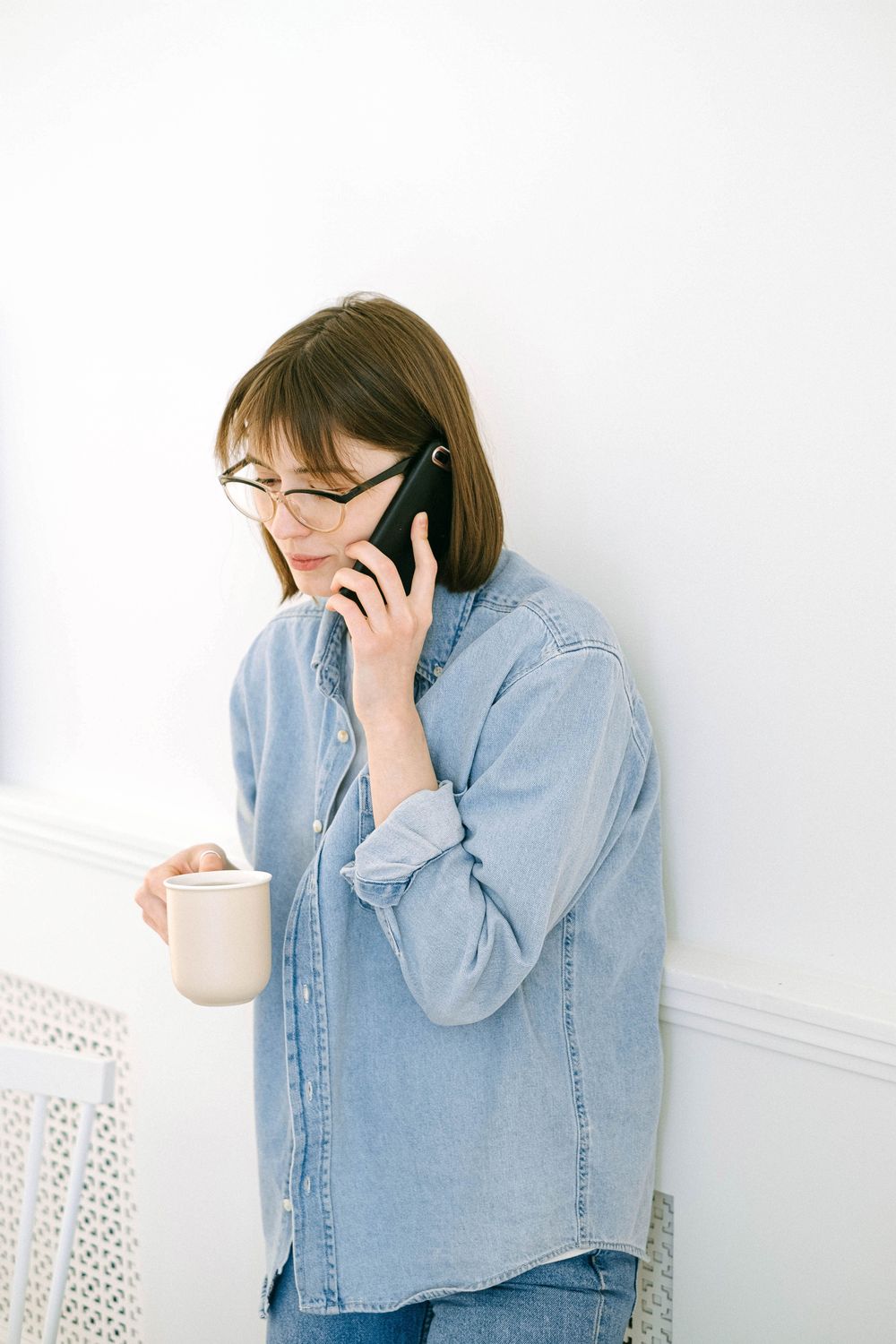 A person holding a coffee mug while talking on the phone.
