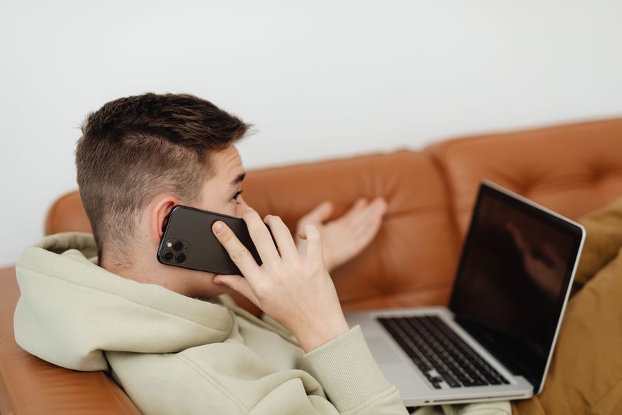 A man on the phone with an open laptop beside him.
